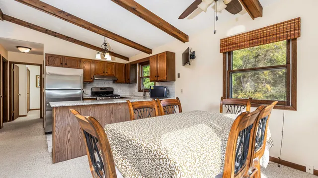 a kitchen with stainless steel appliances granite countertop a refrigerator a sink dishwasher a stove and a dining table with wooden floor