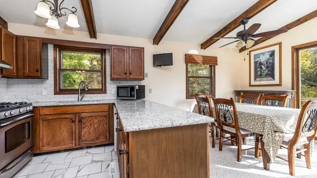 a kitchen with stainless steel appliances granite countertop a stove a sink dishwasher a dining table and chair with wooden floor
