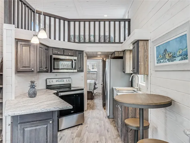 a kitchen with stainless steel appliances granite countertop a sink a stove a refrigerator a dining table and chairs