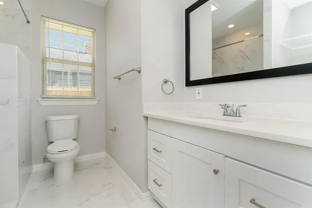 a bathroom with a toilet a sink a mirror and a window