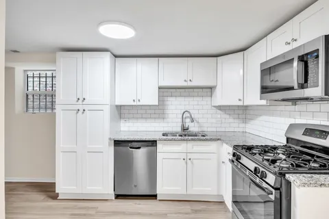 a kitchen with stainless steel appliances white cabinets and stove top oven
