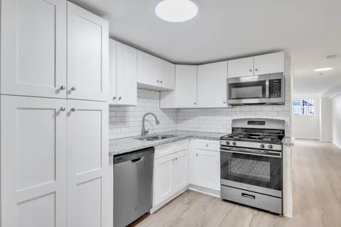 a kitchen with cabinets stainless steel appliances and a window