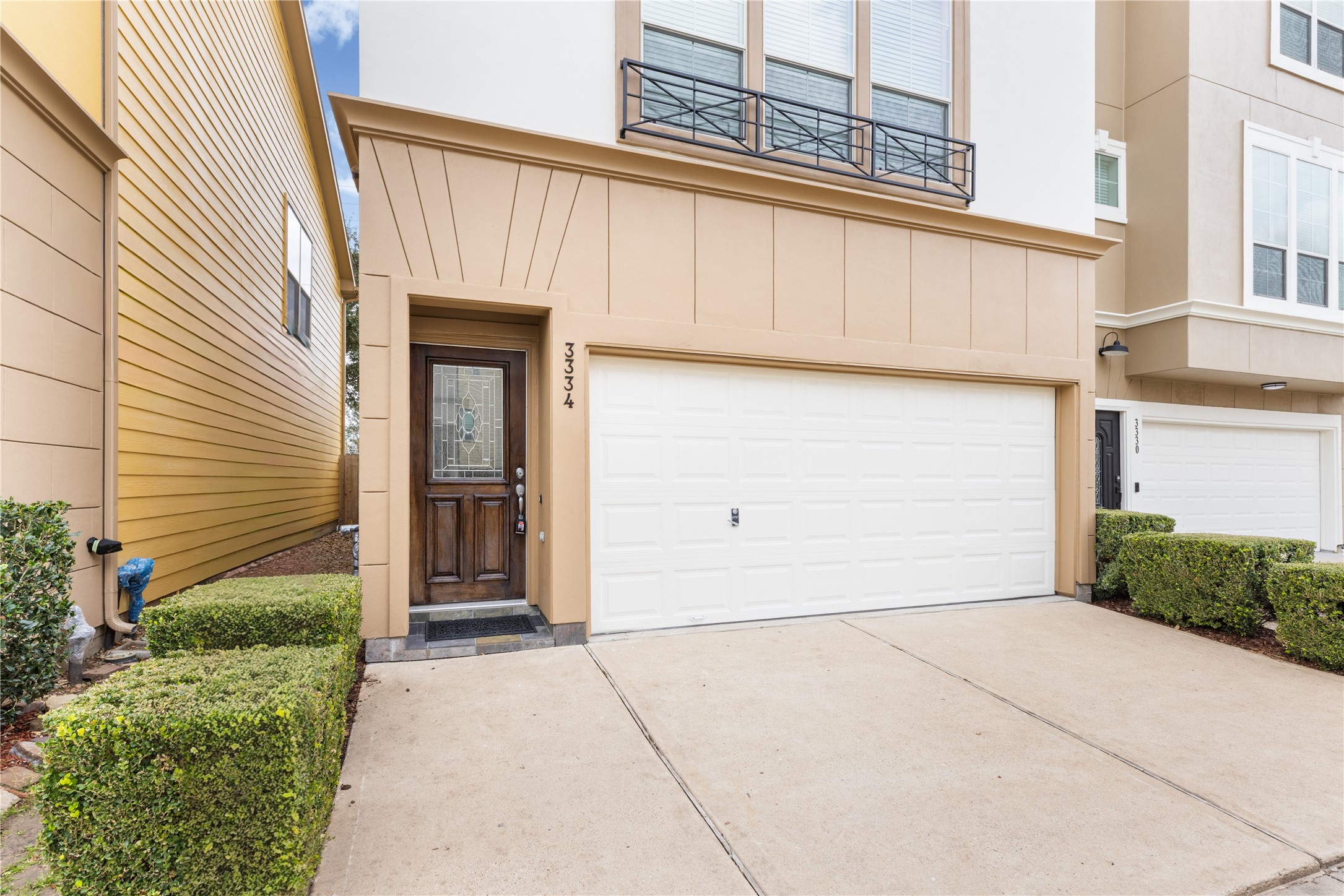 3334 Clearview Villa Way Houston, TX 77025 - Photo 4 of 35 Modern single family house with a two-car garage and covered front door. The exterior features clean lines and neutral tones, with neatly trimmed hedges enhancing curb appeal.