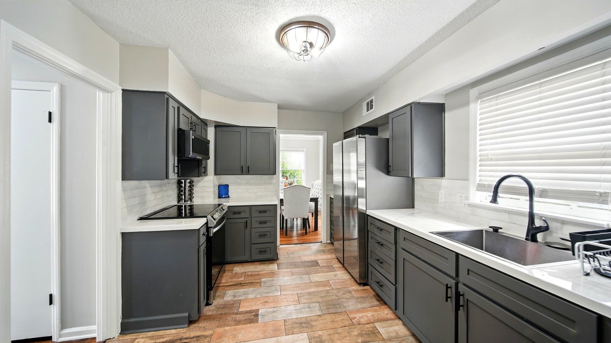 359 South Fenwick Road Memphis, TN 38111 - Photo 12 of 31 Kitchen featuring stainless steel appliances, light stone counters, a textured ceiling, gray cabinets, and tasteful backsplash