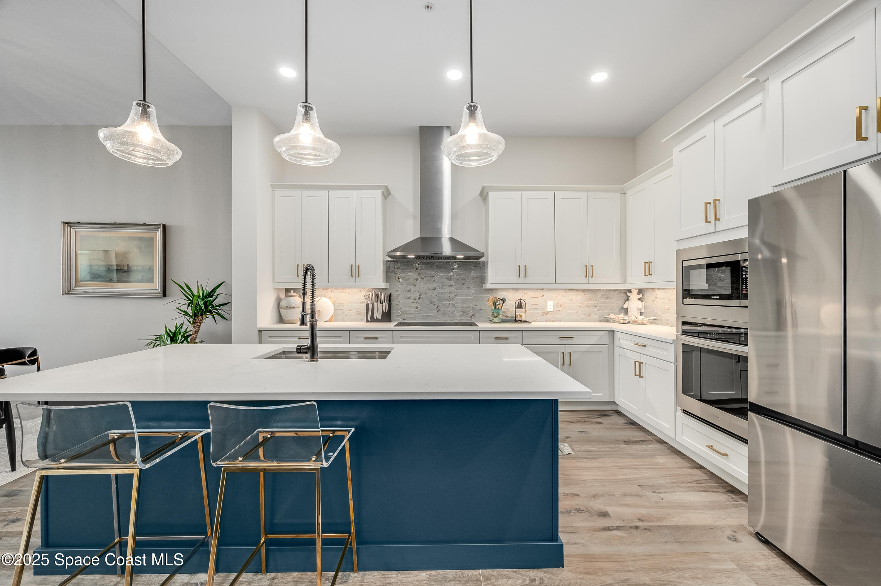 225 Strand Drive, Unit 404 Melbourne Beach, FL 32951 - Photo 27 of 51 a kitchen with kitchen island granite countertop a stove a refrigerator island a sink and white cabinets with wooden floor