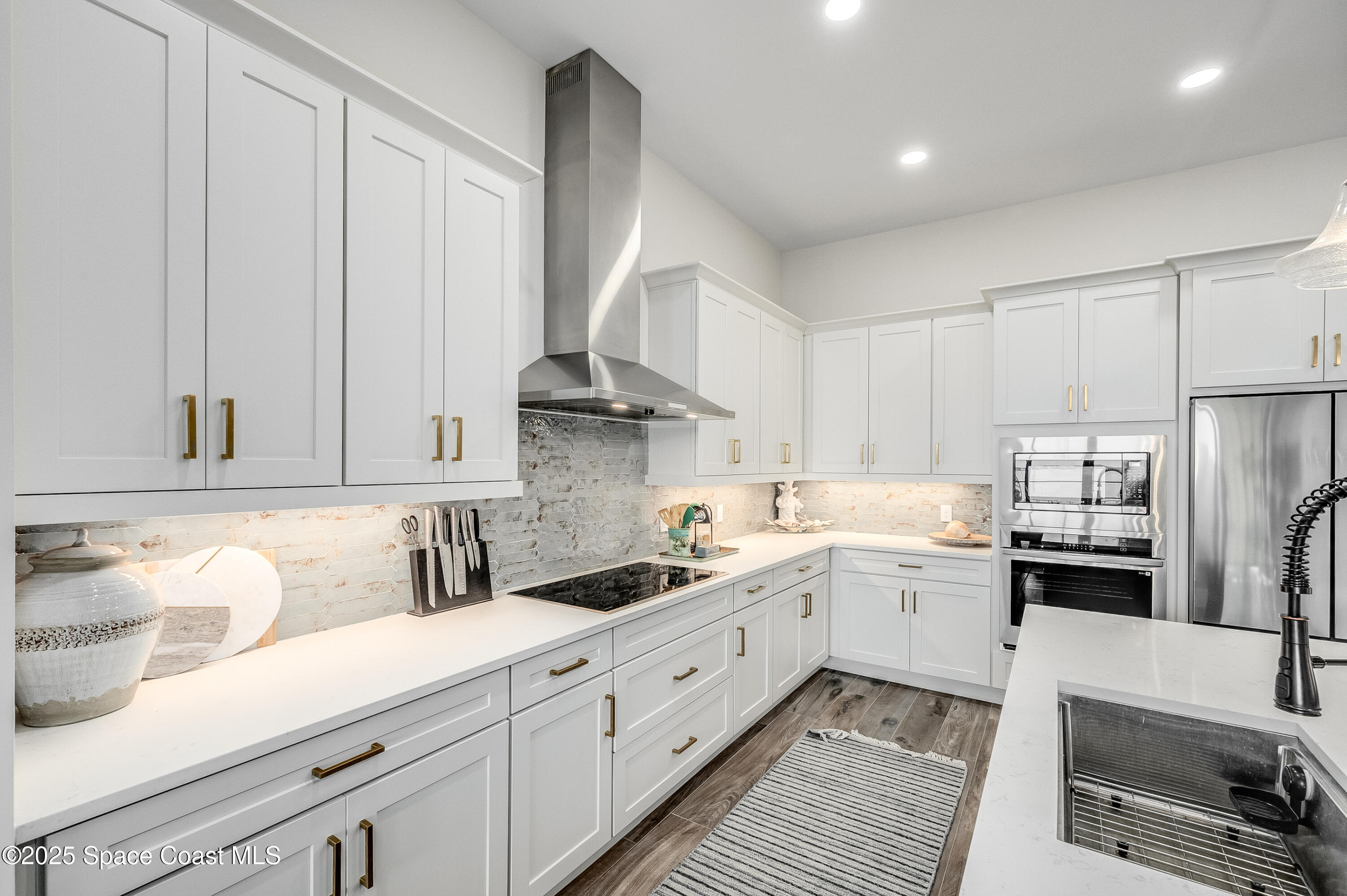 225 Strand Drive, Unit 404 Melbourne Beach, FL 32951 - Photo 31 of 51 a kitchen with white cabinets and stainless steel appliances