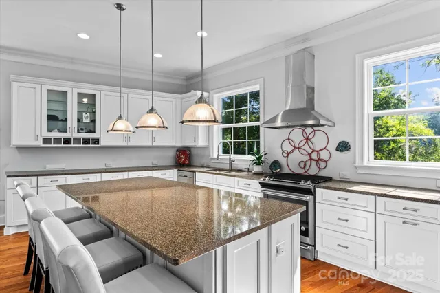 a kitchen with stainless steel appliances granite countertop a sink a stove and a wooden floors