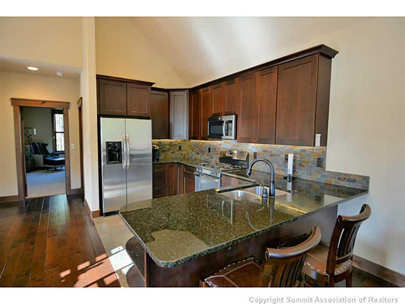853 Independence Road, Unit 5B Keystone, CO 80435 - Photo 7 of 25 a kitchen with stainless steel appliances granite countertop a table chairs and a refrigerator