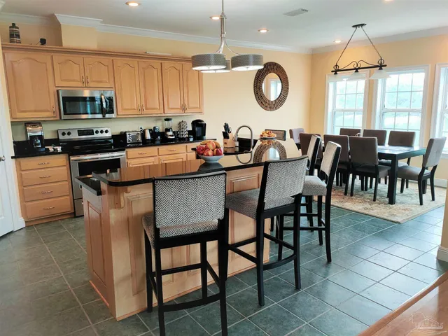 a kitchen with stainless steel appliances granite countertop a stove a sink a dining table and chairs