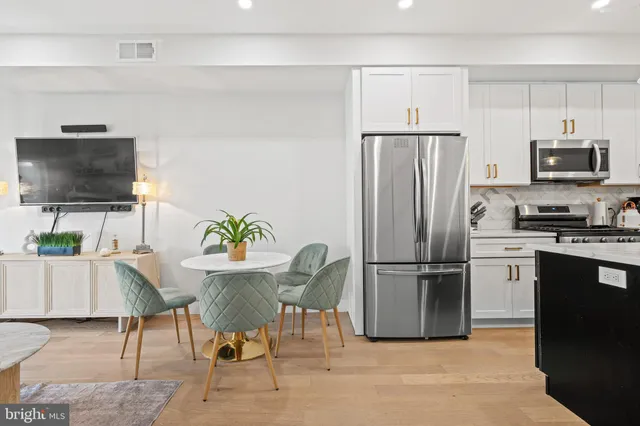 a kitchen with stainless steel appliances a refrigerator a stove a microwave a dining table and chairs with wooden floor