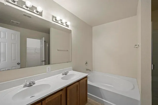 a bathroom with a tub a sink and mirror