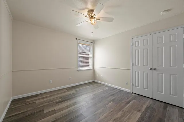 an empty room with wooden floor chandelier fan and windows
