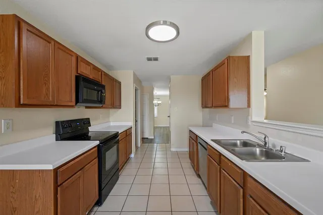 a kitchen with granite countertop a sink a stove top oven and wooden cabinets