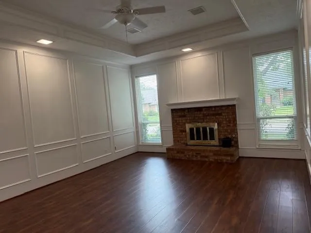 an empty room with wooden floor fireplace and windows