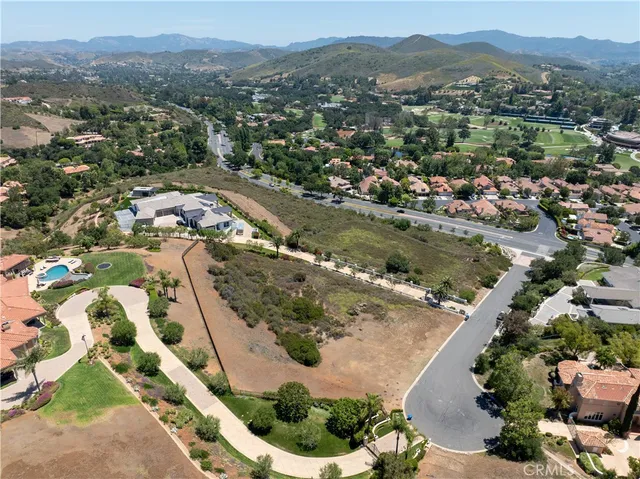an aerial view of residential houses with outdoor space and trees