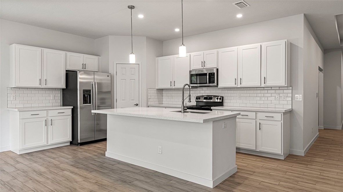 7008 Eden Road Fort Pierce, FL 34951 - Photo 6 of 29 a kitchen with stainless steel appliances a refrigerator stove a sink and white cabinets