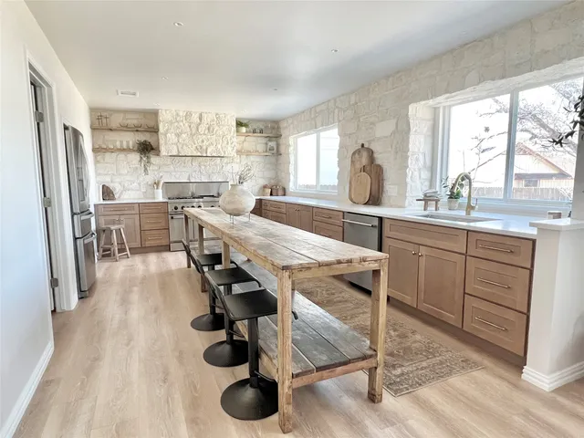 a kitchen with stainless steel appliances granite countertop a stove a sink and a refrigerator