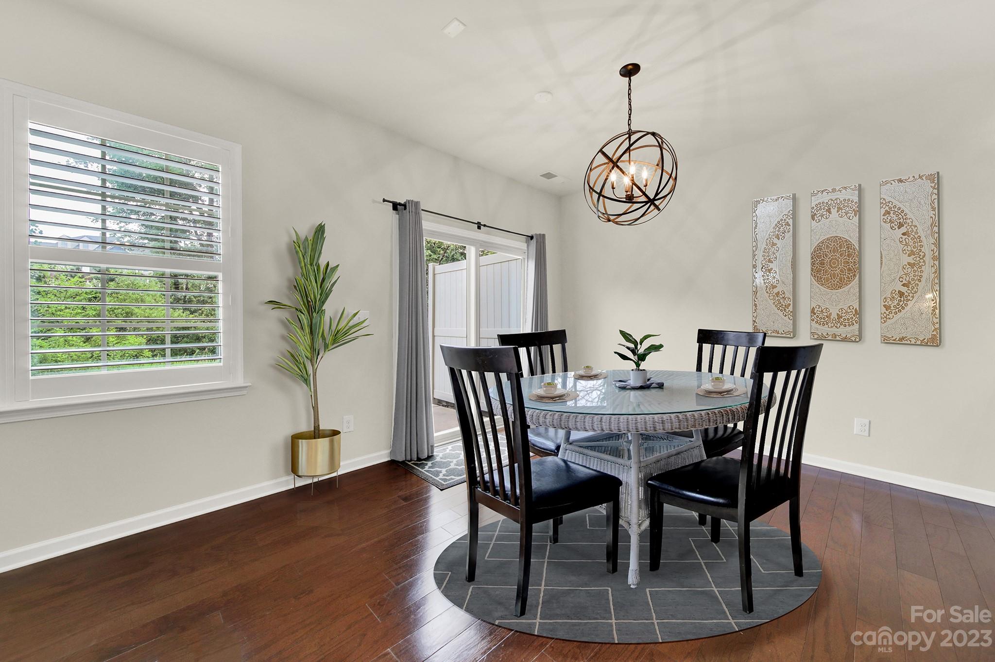 241 Butterfly Place Tega Cay, SC 29708 - Photo 11 of 42 a dining room with wooden floor a chandelier a wooden table and chairs
