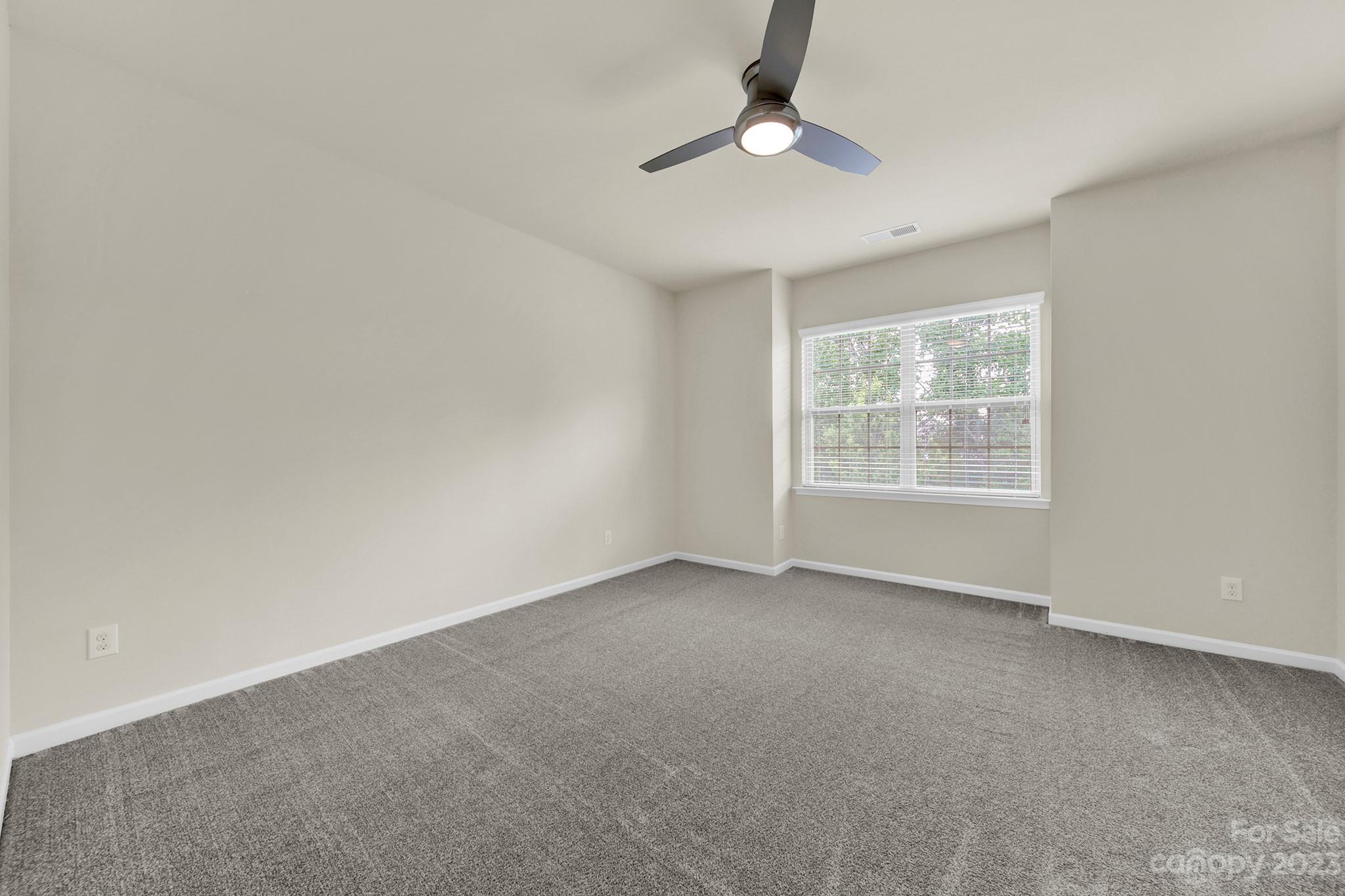 241 Butterfly Place Tega Cay, SC 29708 - Photo 19 of 42 an empty room with a chandelier fan and windows