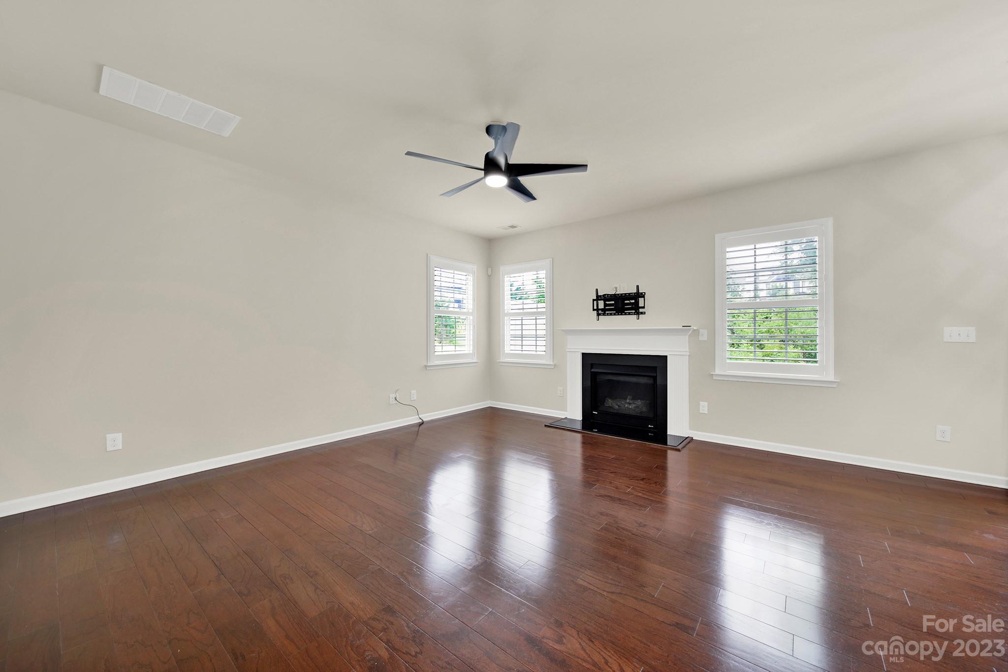 241 Butterfly Place Tega Cay, SC 29708 - Photo 7 of 42 an empty room with wooden floor fireplace and windows