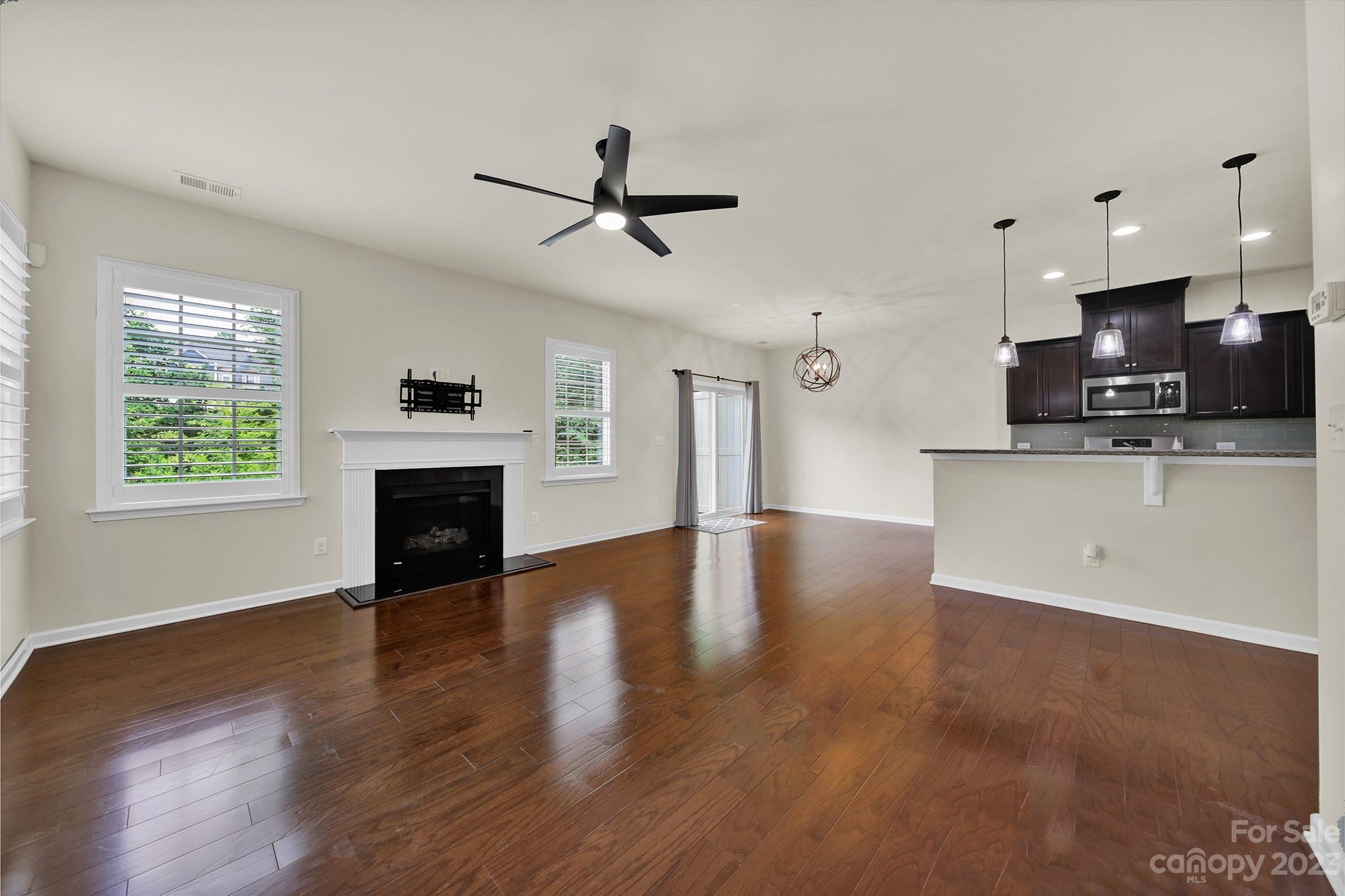 241 Butterfly Place Tega Cay, SC 29708 - Photo 10 of 42 a view of a kitchen with furniture a ceiling fan and wooden floor