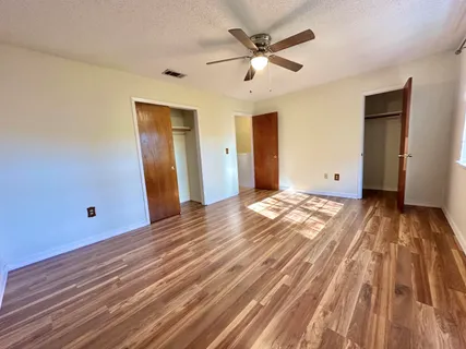 a view of an empty room with window and wooden floor