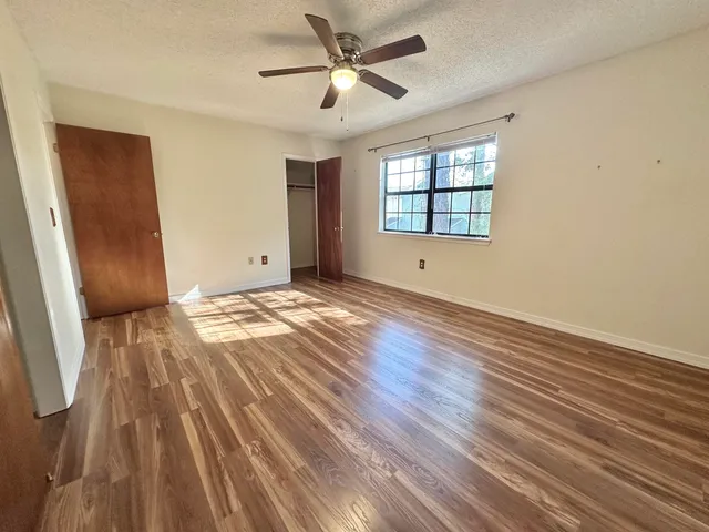 a view of an empty room with wooden floor and a bathroom