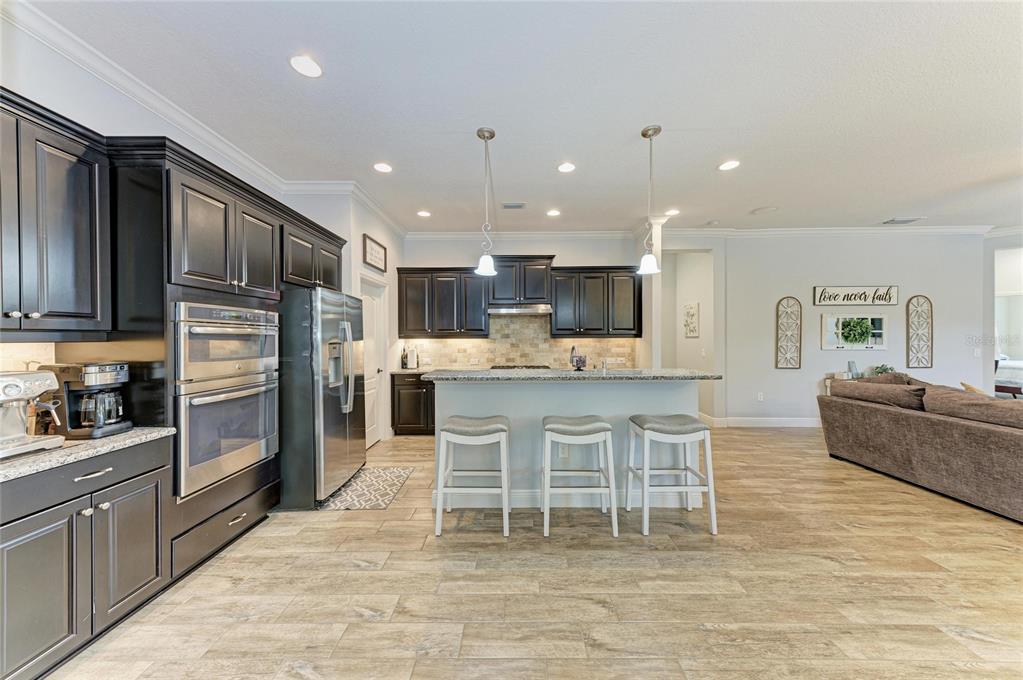 12642 Harney Street Venice, FL 34293 - Photo 14 of 85 a kitchen with stainless steel appliances kitchen island granite countertop a refrigerator and a stove top oven