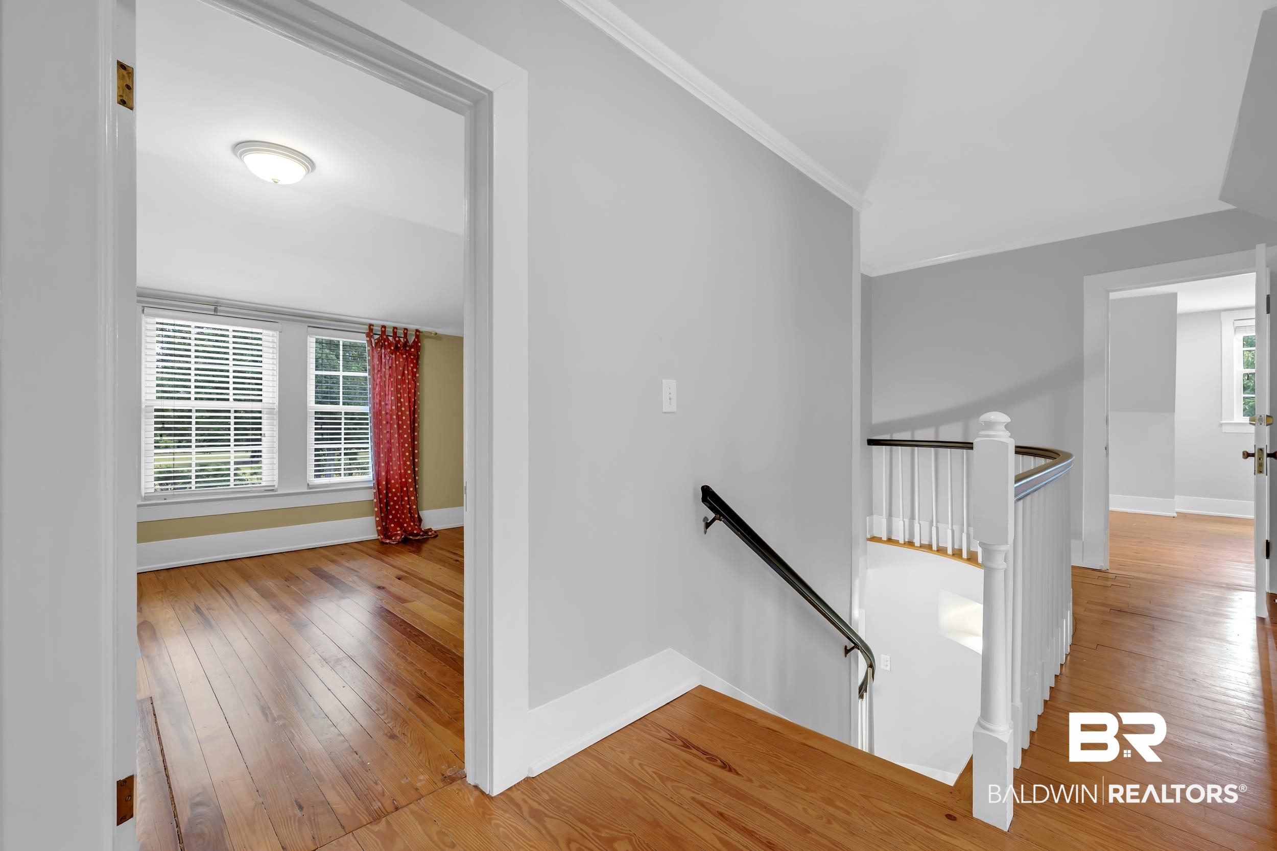 43199 Pine Grove Road Bay Minette, AL 36507 - Photo 56 of 71 Upper-level hallway featuring wood-finish flooring, white trim, and a white baluster staircase with a dark handrail