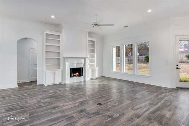 an empty room with wooden floor fireplace and windows