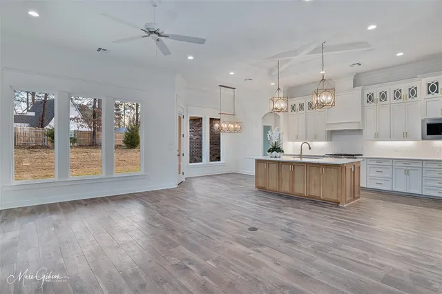 a large kitchen with stainless steel appliances granite countertop a large center island a stove a refrigerator and a wooden floors