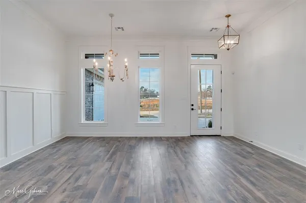 a view of a room with wooden floor chandelier and windows