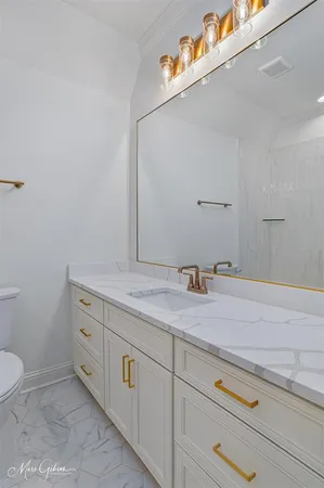 a bathroom with a granite countertop sink and a toilet