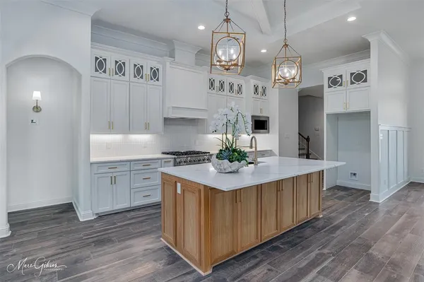 a kitchen with stainless steel appliances granite countertop a white cabinets a sink dishwasher and a stove with wooden floor