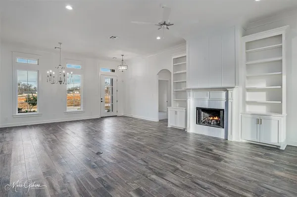 an empty room with wooden floor fireplace and windows