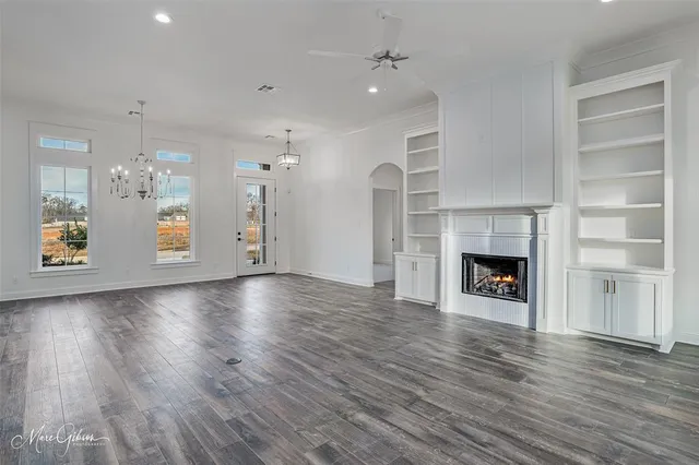 an empty room with wooden floor fireplace and windows