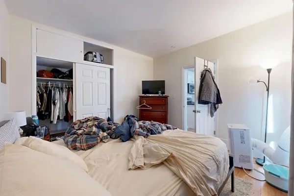 a bedroom with bed a flat tv screen and a closet
