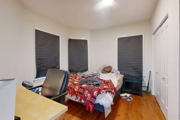 a bedroom with a bed chair and wooden floor