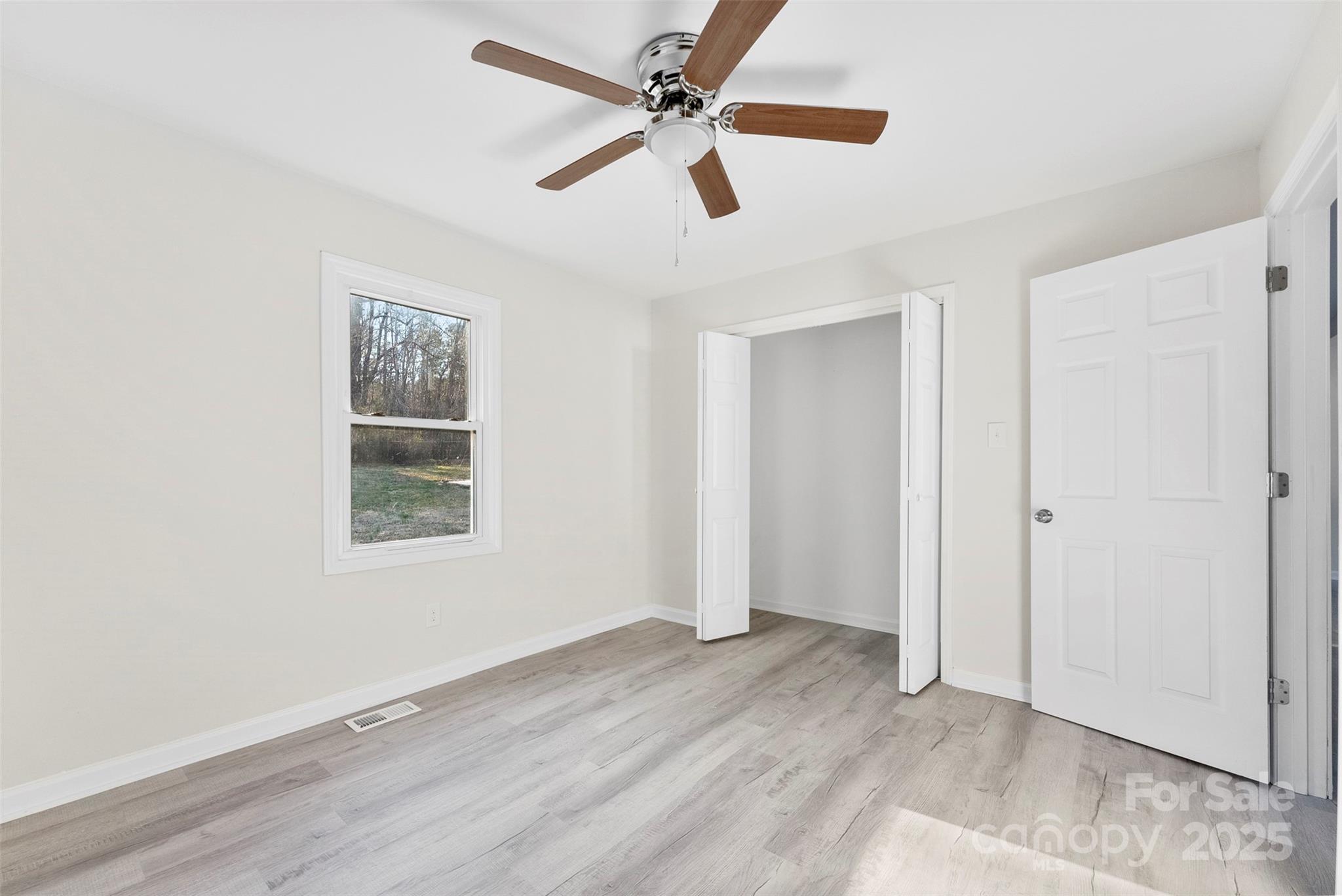 2729 Springbrook Circle Gastonia, NC 28052 - Photo 27 of 37 an empty room with wooden floor ceiling fan and windows