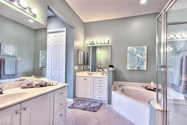 a bathroom with a tub a sink double vanity and glass door