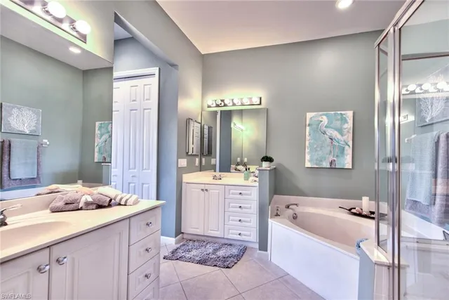 a bathroom with a tub a sink double vanity and glass door