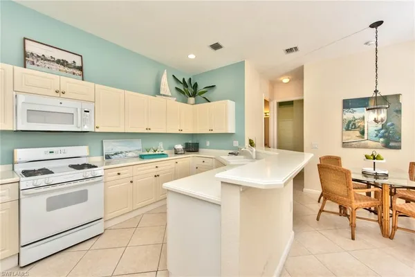 a kitchen with a sink a stove a refrigerator and white cabinets