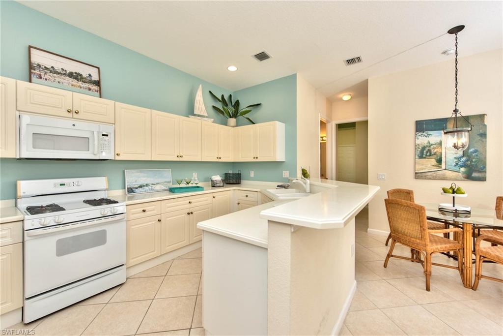 4529 Cardinal Cove Lane, Unit 7 Naples, FL 34114 - Photo 7 of 26 a kitchen with a sink a stove a refrigerator and white cabinets