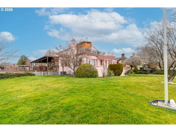 a view of a house with a big yard and potted plants in front of the house