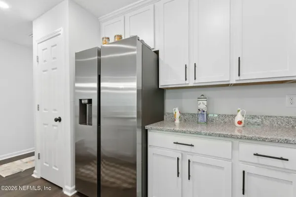 a kitchen with granite countertop a refrigerator and cabinets