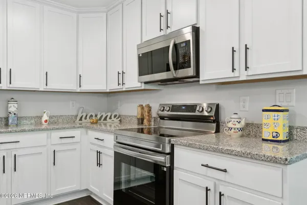 a kitchen with stainless steel appliances granite countertop a sink a stove and microwave with wooden cabinets