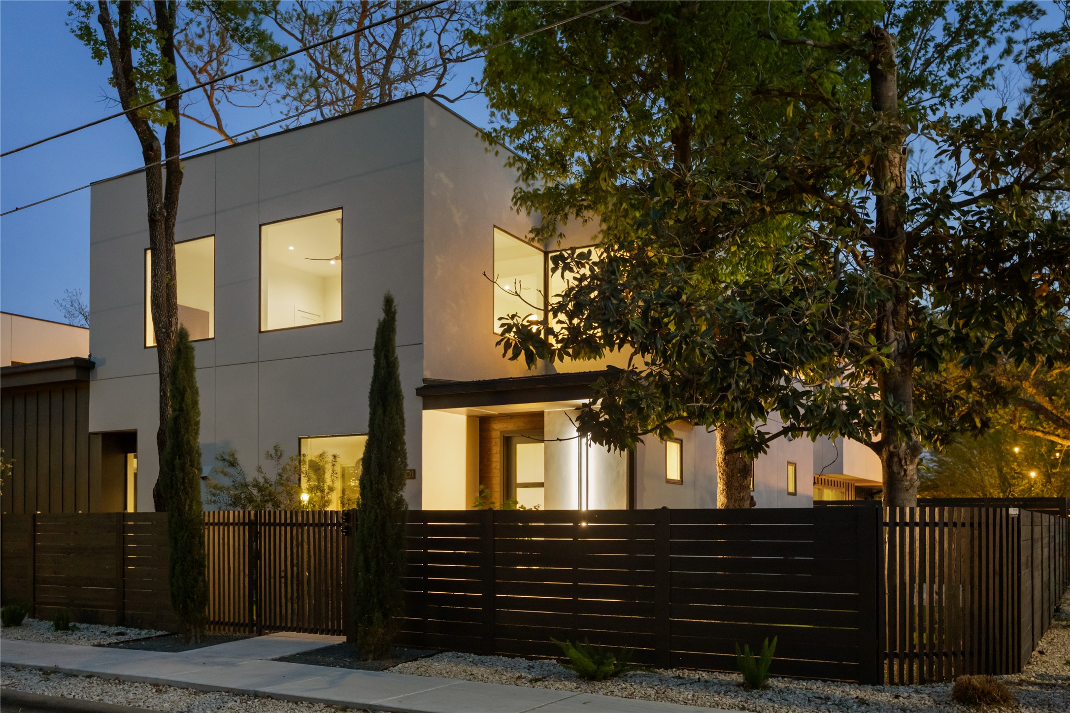 3201 Holton Street Austin, TX 78702 - Photo 1 of 39 Sleek modern architecture and a striking gated facade set a sophisticated tone for this exceptional East Austin residence at dusk.
