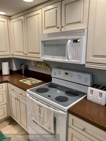 a kitchen with granite countertop white cabinets and white appliances