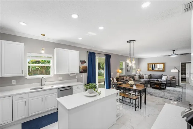 a kitchen with stainless steel appliances a stove a sink a microwave a refrigerator a stove and white cabinets