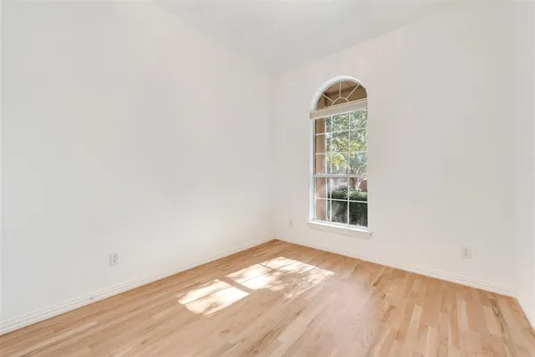 an empty room with wooden floor cabinets and a window